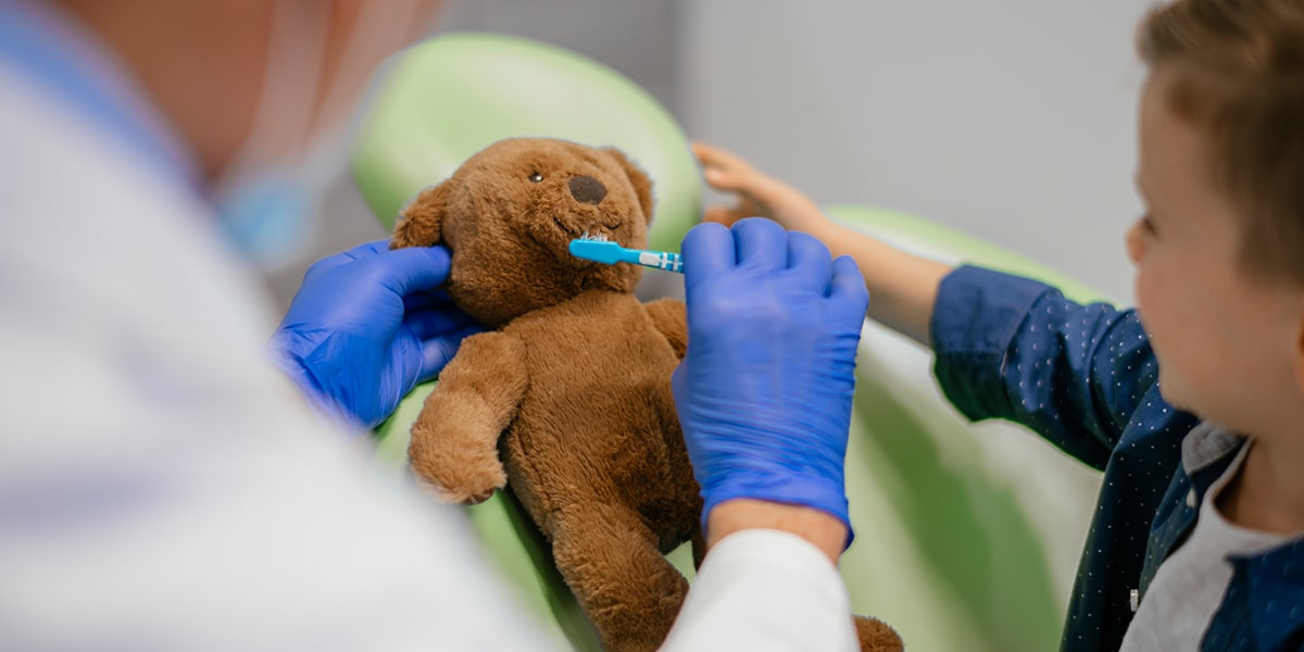 Child Brushing Teddy Bear's Teeth Image