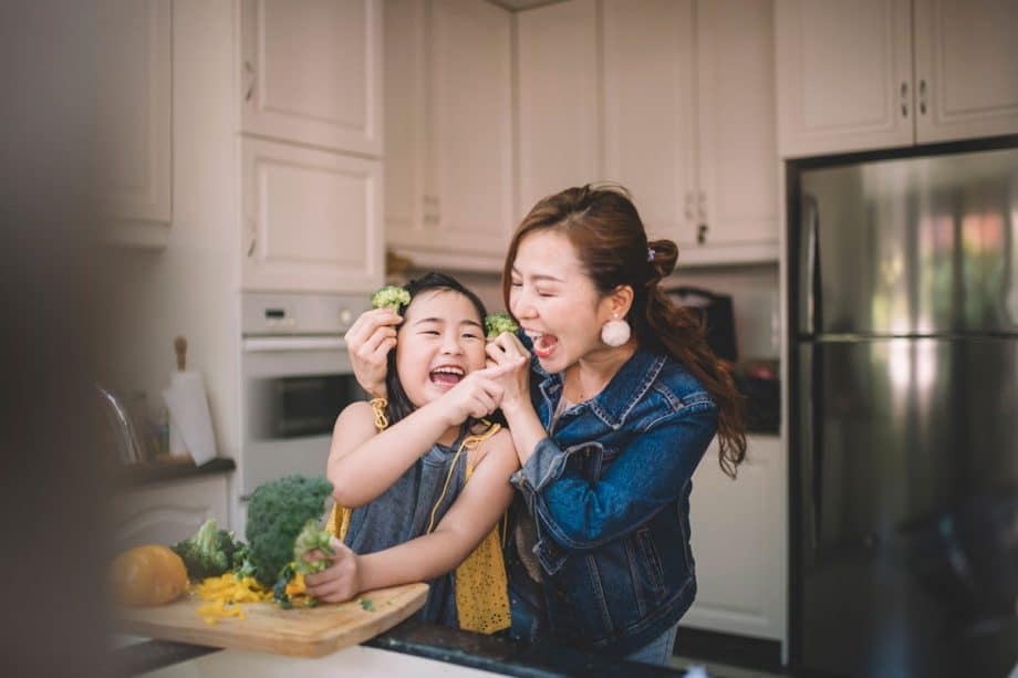 Mother and daughter laughing and preparing food in kitchen