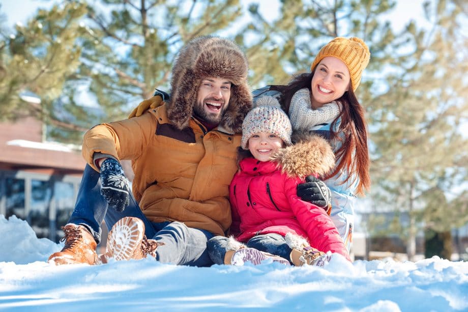 parents and child laugh in the snow